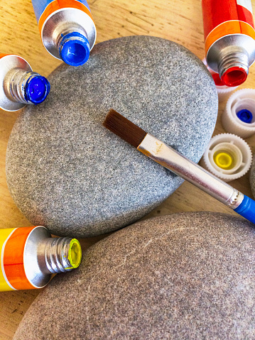 Two pebbles with paint tubes and brush.