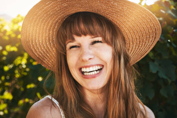 Beautiful young redhead in straw sunhat laughs happily A lovely young woman with long red hair  ad very fair skin laughs happily as she stands in the sunshine wearing a sunhat. pale complexion stock pictures, royalty-free photos & images