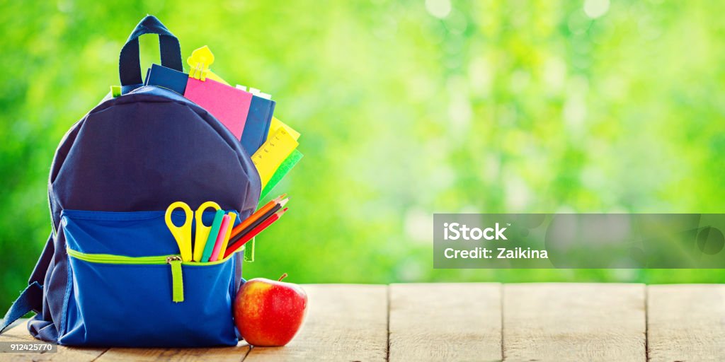 Banner. Full School backpack with apple on wooden and nature green background. Banner. Full School backpack with apple on wooden and nature green background Back to School Stock Photo