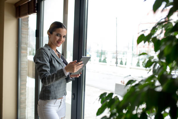 istock Businesswoman next to window is using tablet 912430252