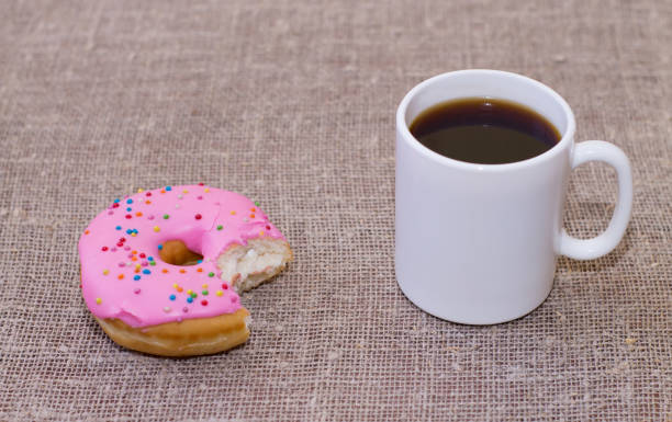 istock Donut with icing on the table. Nearby is a mug with coffee. Sweet colored donut 912430502
