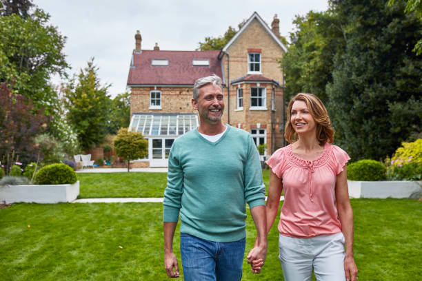 istock Happy couple holding hands on field against house 912438076