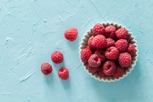 Raspberries in bowl, top view, copy space