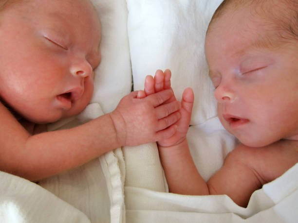 pasgeboren prematuur twins hand in hand - eeneiige tweeling stockfoto's en -beelden