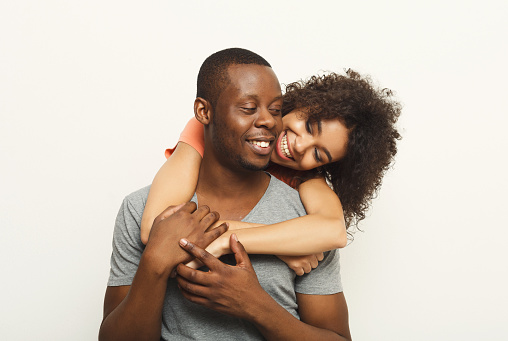 Studio shot of happy casual african-american couple embracing, posing to camera and smiling on white studio background, copy space, isolated