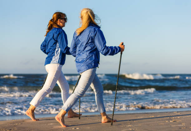 nordic walking - aktive menschen, die arbeiten am strand - power walken stock-fotos und bilder