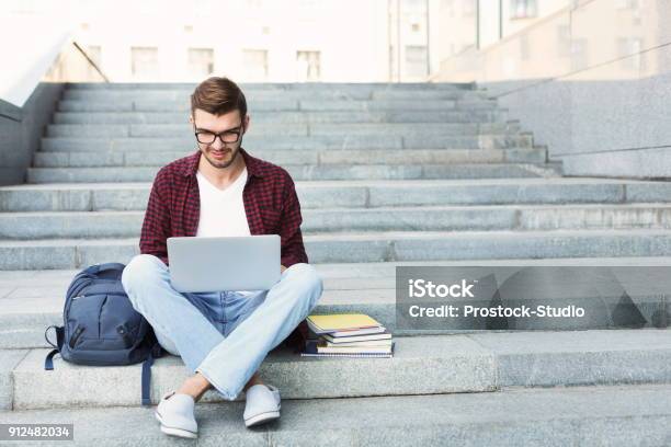 Estudiante Sonriente Sentado En Las Escaleras Usando Laptop Foto de stock y más banco de imágenes de Estudiante de universidad