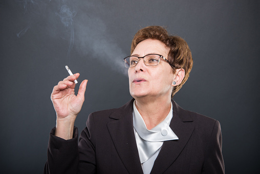 Business senior lady enjoying smoking cigarrete on black background