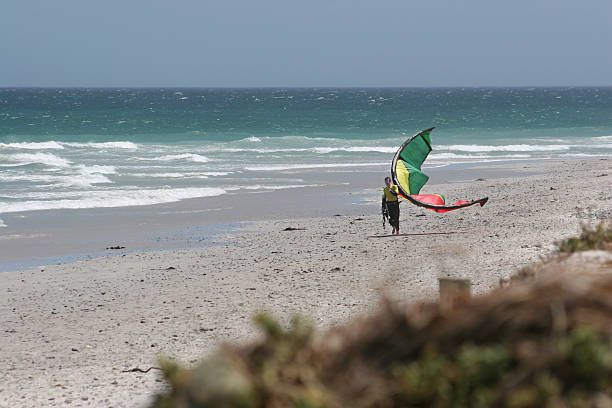 istock Kitesurfer walkes on the beach with his kite 91250230