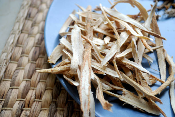 Huang Qi (Astragalus) root sliced and dried on a plate.