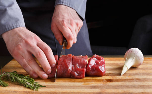 istock Chef cutting filet mignon on wooden board at restaurant kitchen 912506628