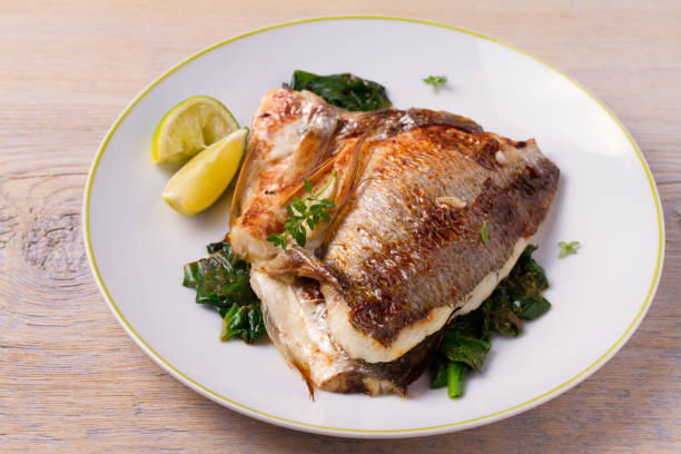 istock Roasted sea bream with spinach. Dorado or dorada fish fillet on white plate 912507332