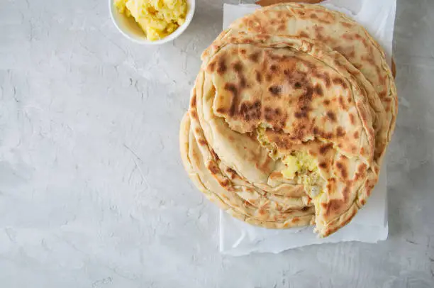 Mashed potato and sheep cheese filling flatbread on a white stone background.