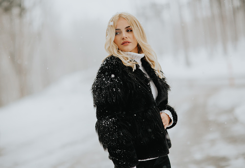 Portrait of blonde woman outside in snow winter coat
