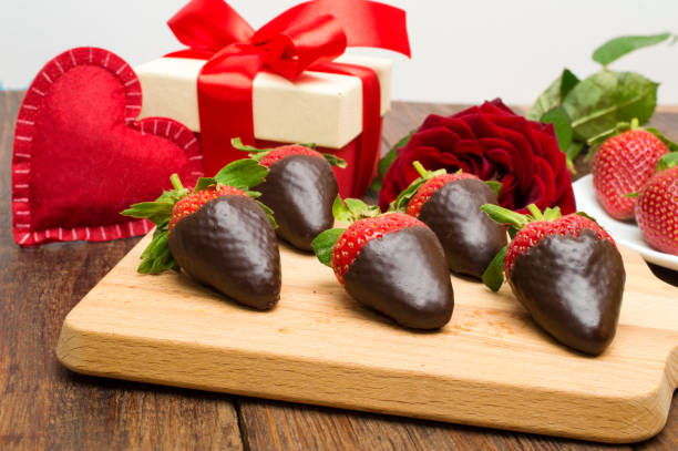 fragole fresche i immersioni in cioccolato fondente, regalo e cuore su sfondo di legno. san valentino. - chocolate dipped foto e immagini stock