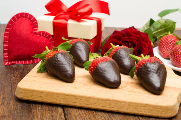 Fresh strawberries dipped in dark chocolate, gift and heart on wooden background. Valentine's Day. Valentine's Day. Fresh strawberries dipped in dark chocolate, gift and heart on wooden background. chocolate covered strawberries stock pictures, royalty-free photos & images