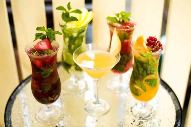 Photo of Alcohol bar, cocktail glass on bar counter, cocktail glass in a bar, Drinking cocktail in bar, cocktail in the glass with straws, Fresh drink coctail on a color background