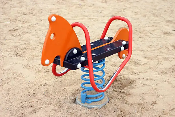 Empty colorful rocking horse on sandy playground outdoors