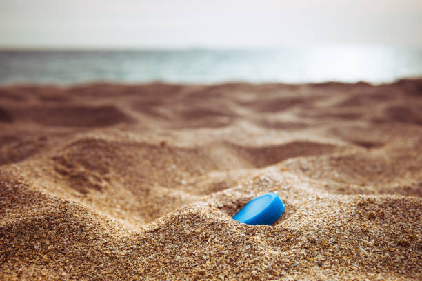 scartato bottiglia di plastica top inquinamento spazzatura sulla spiaggia - plastic lid foto e immagini stock