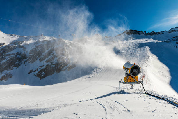 nieve - cañón de nieve trabajando en la ladera - mountain winter season machine snow making machine fotografías e imágenes de stock