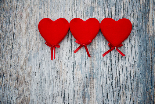 Three red hearts on a wooden background with copy space