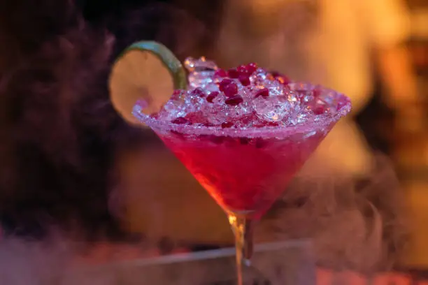 Photo of Alcohol bar, cocktail glass on bar counter, cocktail glass in a bar, Drinking cocktail in bar, cocktail in the glass with straws, Fresh drink coctail on a color background