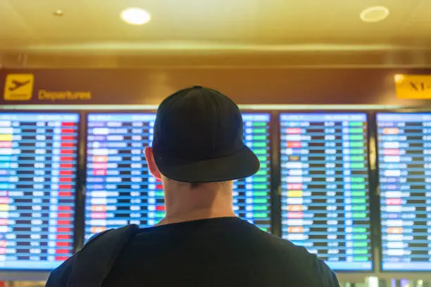 Man looking the timetable of a flight board in airport for departures