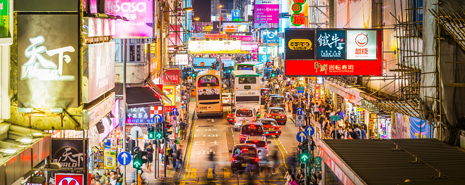 Elevated panoramic view across the vibrant neon signs and busy city streets of Kowloon at night, Hong Kong, China.