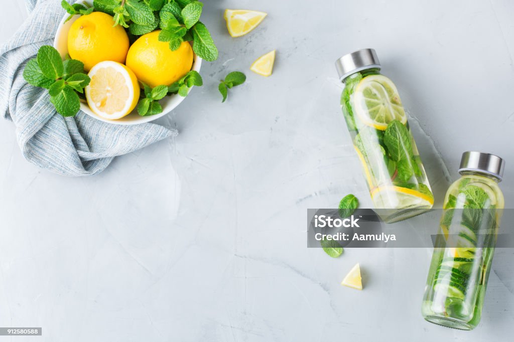 Fresh cool lemon cucumber mint infused water detox drink Health care, fitness, healthy nutrition diet concept. Fresh cool lemon cucumber mint infused water, cocktail, detox drink, lemonade in a glass jar. Light top view flat lay background Detox Stock Photo