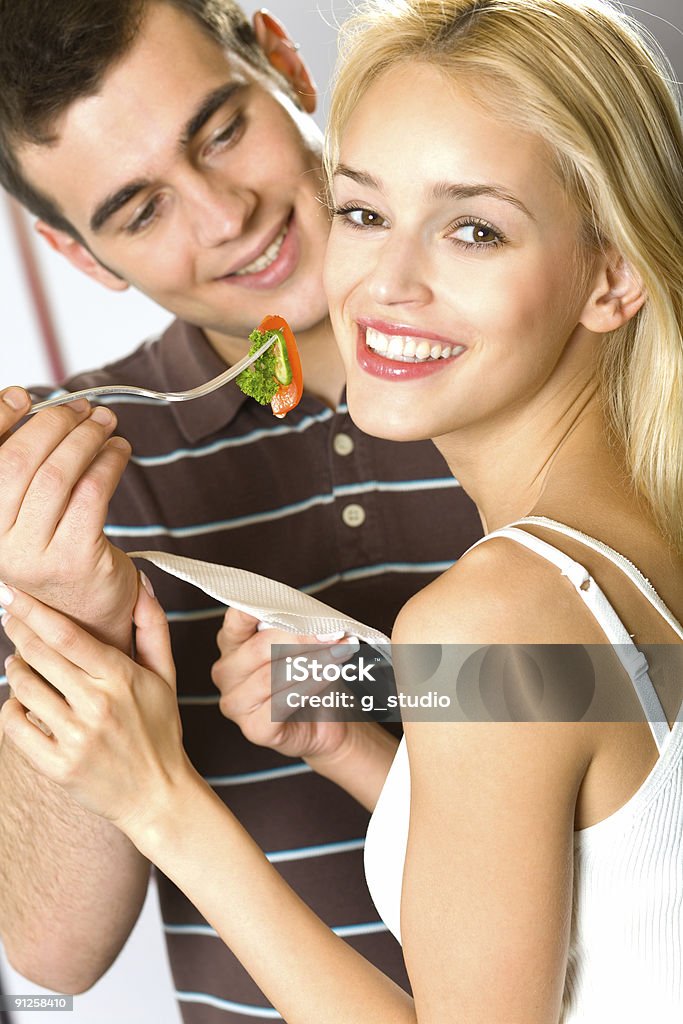 Jovem atraente, sorrindo alegremente casal feliz comendo vegetais, interior - Foto de stock de Adulto royalty-free
