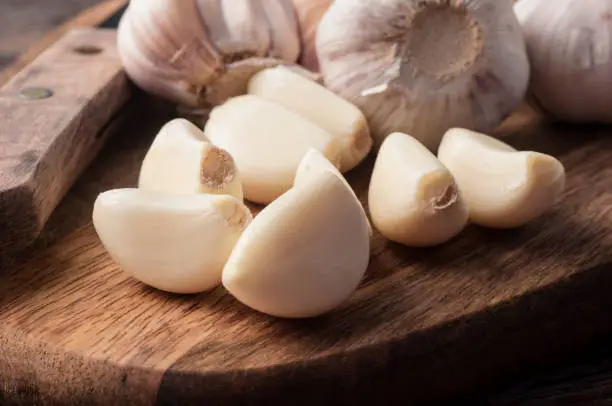 Sliced Garlic and garlic bulb on vintage wooden background. Place for text, copy space. Concept of healthy food.