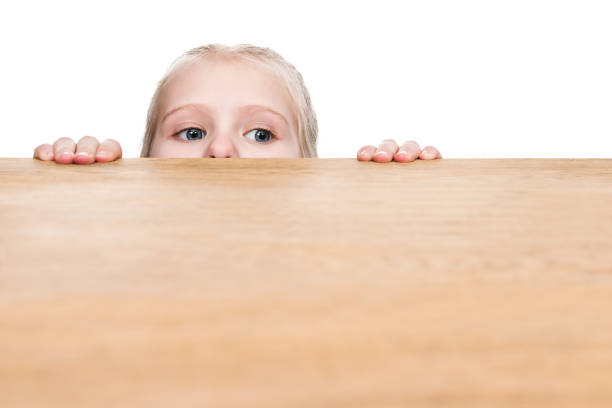 子は、テーブルの下から外を見てください。 - peeking ストックフォトと画像