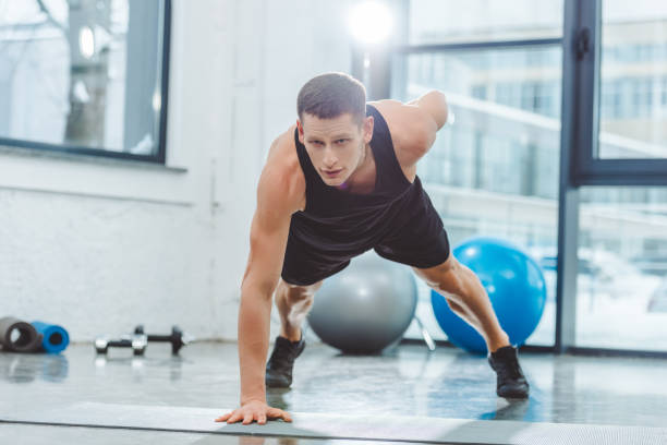 istock handsome young sportsman doing push ups on yoga mat 912592034