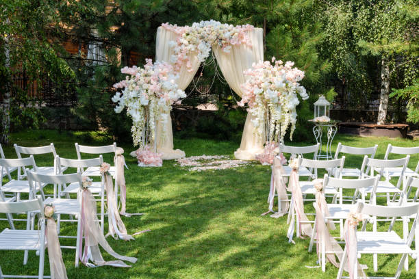 istock Wedding arch decorated with cloth and flowers outdoors. Beautiful wedding set up. Wedding ceremony on green lawn in the garden. Part of the festive decor, floral arrangement. 912597002