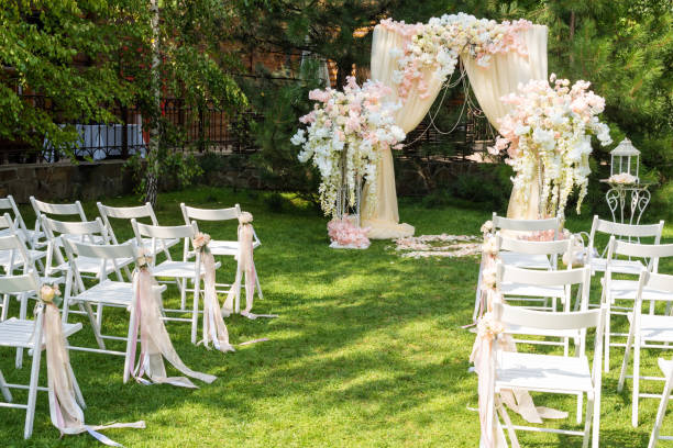 istock Wedding arch decorated with cloth and flowers outdoors. Beautiful wedding set up. Wedding ceremony on green lawn in the garden. Part of the festive decor, floral arrangement. 912597006