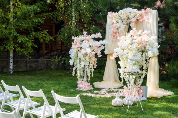 istock Wedding arch decorated with cloth and flowers outdoors. Beautiful wedding set up. Wedding ceremony on green lawn in the garden. Part of the festive decor, floral arrangement. 912597008