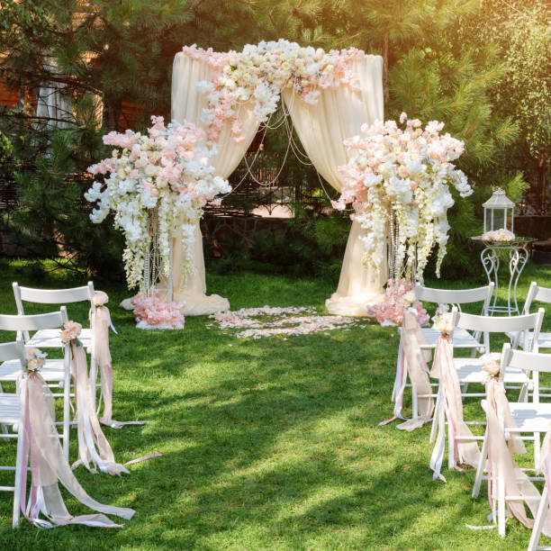 istock Wedding arch decorated with cloth and flowers outdoors. Beautiful wedding set up. Wedding ceremony on green lawn in the garden. Part of the festive decor, floral arrangement. 912597012
