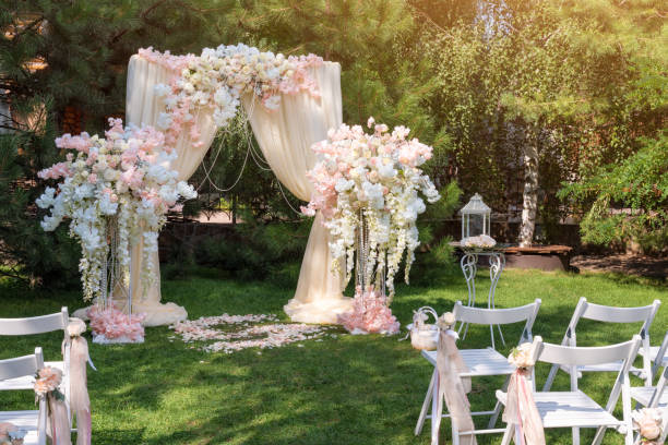 istock Wedding arch decorated with cloth and flowers outdoors. Beautiful wedding set up. Wedding ceremony on green lawn in the garden. Part of the festive decor, floral arrangement. 912597014