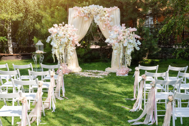 istock Wedding arch decorated with cloth and flowers outdoors. Beautiful wedding set up. Wedding ceremony on green lawn in the garden. Part of the festive decor, floral arrangement. 912597018