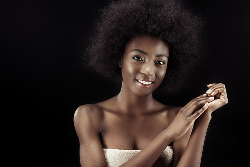 attractive african american woman covered with towel isolated on black