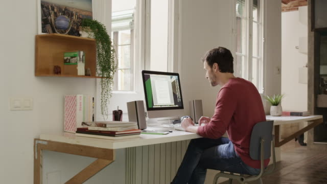 Hombre con ayuda de ordenador mientras habla por teléfono en el hogar photo
