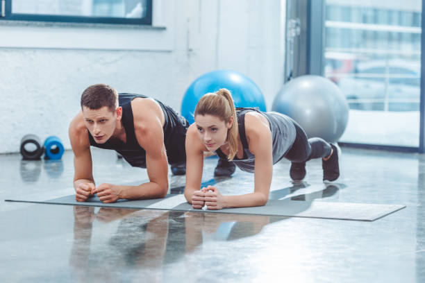 istock sporty young couple doing plank exercise in gym 912603066