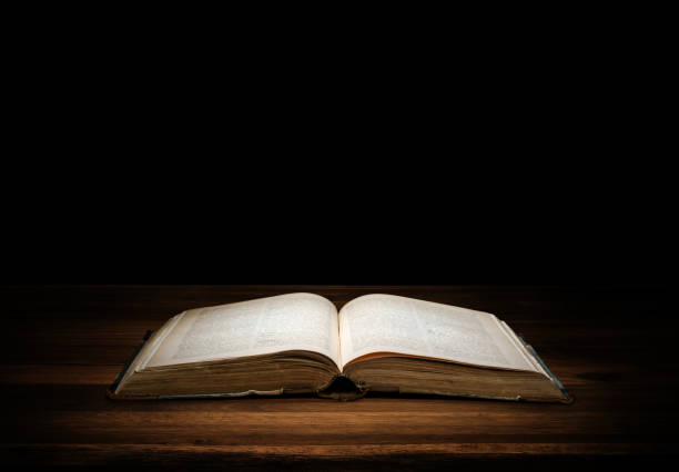 istock old book on wood desk isolated on black. 912611494