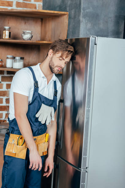istock tired young foreman with tool belt leaning at broken refrigerator 912617104