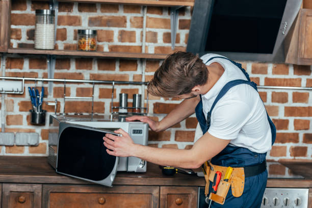 istock professional young foreman repairing microwave oven in kitchen 912617178
