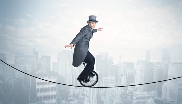 istock Brave guy riding a monocycle on a rope above cityscape 912621144