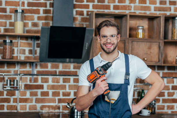 istock handsome young man holding electric drill and smiling at camera 912621864