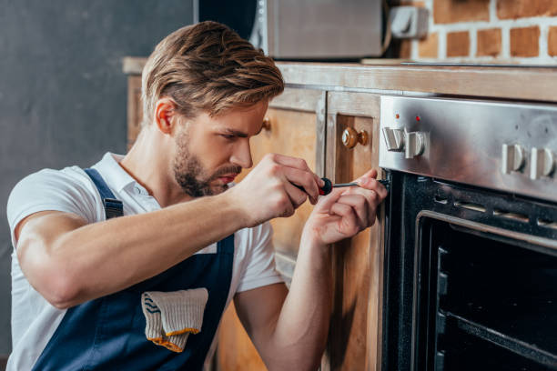 istock handsome young repairman fixing oven with screwdriver 912624896