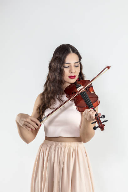 istock Beautiful young woman playing violin over white background 912625234