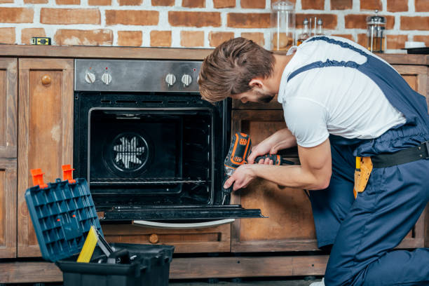 istock young repairman in protective workwear fixing oven with electric drill 912625358